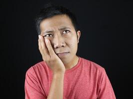 funny expression of confused asian man with hand on chin photo