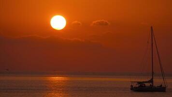 Tranquil golden sunset over calm sea with distant horizon serene ocean landscape. Yacht silhouette floating video