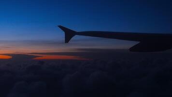 Amazing skyscape view in the sky with sunset, wing and turbine from porthole. Beautiful views from the plane. Traveling by airplane at night video