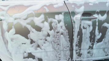 Car washing, white active foam on surface of body. video