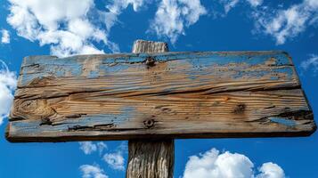 A wooden sign is placed on top of a wooden pole outdoors photo