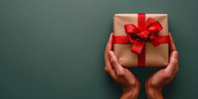 Person Holding Wrapped Gift Box With Red Bow photo