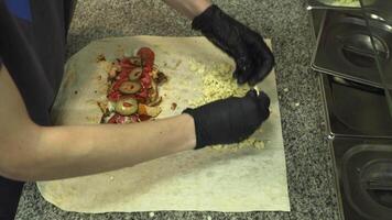 We prepare shawarma from vegetables and meat. Delicious fatty junk food being prepared for takeaway in a diner. Cooking shawarma instead of fast food video