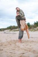 A tender moment between a couple on a sandy beach, as a man holds a woman close, their affectionate embrace conveying a sense of comfort and connection in a serene coastal setting. photo