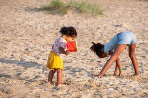 Two children, sisters, play independently with sand toys on a beach, a scene of shared yet individual play, national siblings day and playing in nature. photo