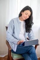 Happy middle aged female using a tablet, reflecting engagement with digital media in her mature years, a blend of comfort and tech, and life long learning. photo