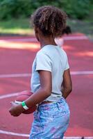 posterior ver de un africano americano niña participación un baloncesto en el corte, listo a jugar, capturar un momento de anticipación y deportividad, Deportes ocupaciones desde un joven edad. foto