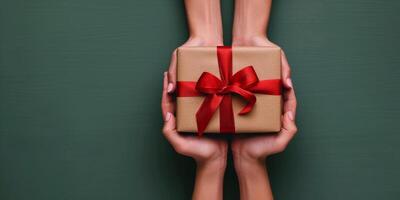 Two Hands Holding a Wrapped Gift Box With a Red Bow photo