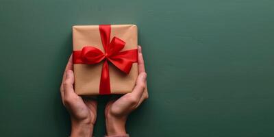 Person Holding Wrapped Gift Box With Red Bow photo