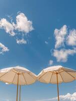 Two White Umbrellas on Sandy Beach photo