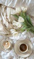 A Cup of Coffee and a Vase of Flowers on a Bed photo