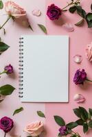 Spiral Notebook Surrounded by Flowers on Pink Background photo