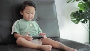 Child playing games by smartphone on sofa video