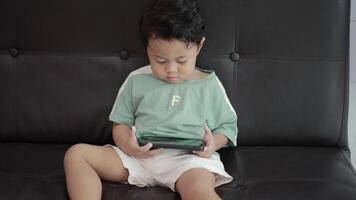 Child playing games by smartphone on sofa video