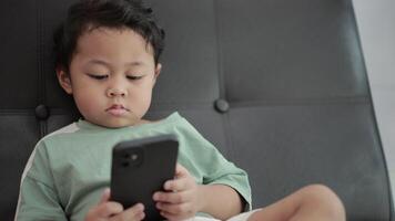 Child playing games by smartphone on sofa video