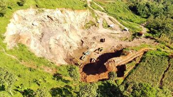 Aerial view of earthworks progress such as gravel quarry and professional excavators at the construction site. Mining destroys the ecosystem of living things in the Mountain. Construction industry. 4k video