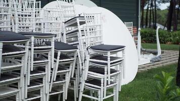 White chairs and tables are neatly stacked outside to create an orderly event arrangement video
