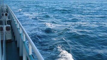 A boat sails on the open ocean, leaving a wake under the blue sky and on the tranquil waters video