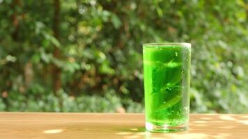 Colorful soft drinks poured into glasses and placed on the table. There is a natural background. video