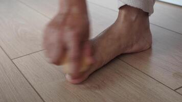 utilizzando un' spazzola, il persona delicatamente spazzole loro piede su il legno duro pavimentazione video