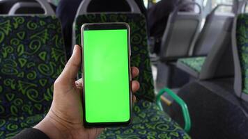 passager séance dans une autobus en utilisant le sien téléphone avec vert écran video