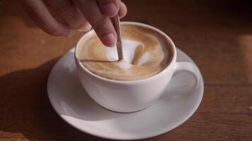 person hand stirring coffee with spoon. video