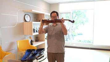 Asian man playing violin in room video