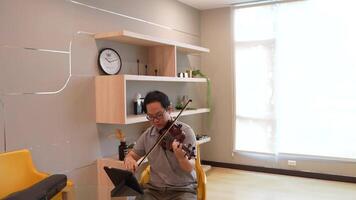 Asian man playing violin in room video