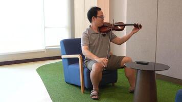 asiático hombre jugando violín en habitación video