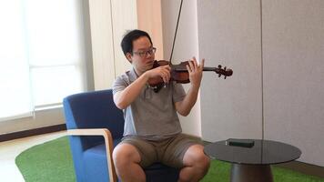 Asian man playing violin in room video