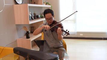 Asian man playing violin in room video