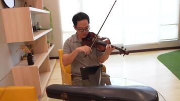 Asian man playing violin in room video
