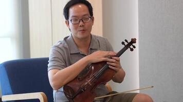 asiático hombre jugando violín en habitación video