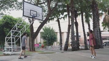 el masculino y hembra baloncesto jugadores práctica utilizando el pelota en el parque Corte diligentemente y felizmente. video