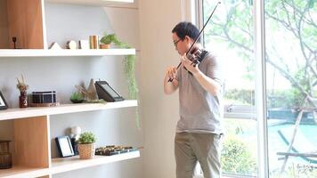 Asian man playing violin in room video