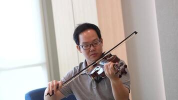 Asian man playing violin in room video