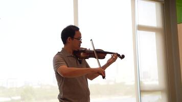 Asian man playing violin in room video