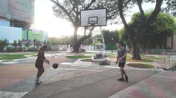 de manlig och kvinna basketboll spelare öva använder sig av de boll i de parkera domstol flitigt och lyckligt. video