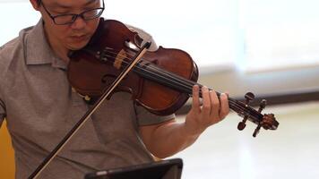 Asian man playing violin in room video