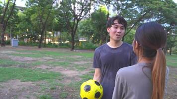 mannetje en vrouw voetbal spelers praktijk gebruik makend van de bal in de park veld- ijverig en gelukkig. video