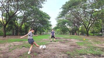 manlig och kvinna fotboll spelare öva använder sig av de boll i de parkera fält flitigt och lyckligt. video