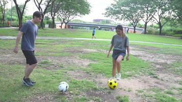 masculino y hembra fútbol jugadores práctica utilizando el pelota en el parque campo diligentemente y felizmente. video