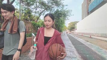 The male and female basketball players practice using the ball in the park court diligently and happily. video