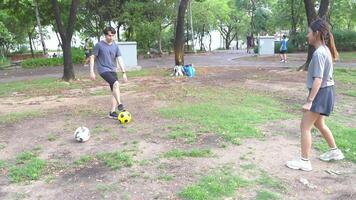 masculino y hembra fútbol jugadores práctica utilizando el pelota en el parque campo diligentemente y felizmente. video