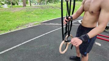 asiatisk man praktiserande gymnastik håller på med gymnastik bar och ring övningar och stretching och vilar för sporter. video