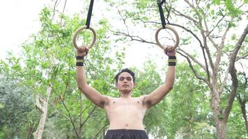 Asian man practicing gymnastics doing gymnastics bar and hoop exercises and stretching and resting for sports. video