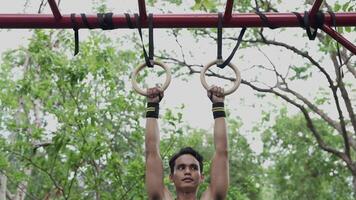 Asian man practicing gymnastics, doing gymnastics bar and hoop exercises and stretching, resting for sports. video