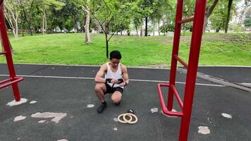 asiatisk man praktiserande gymnastik håller på med gymnastik bar och ring övningar och stretching och vilar för sporter. video