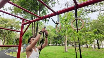 Asian man practicing gymnastics doing gymnastics bar and hoop exercises and stretching and resting for sports. video