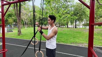 Asian man practicing gymnastics doing gymnastics bar and hoop exercises and stretching and resting for sports. video